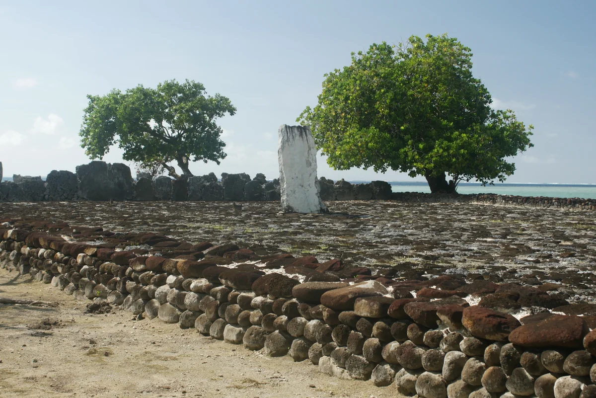 Stone courtyard, standing stone and trees at the Taputapuātea marae on Raiatea